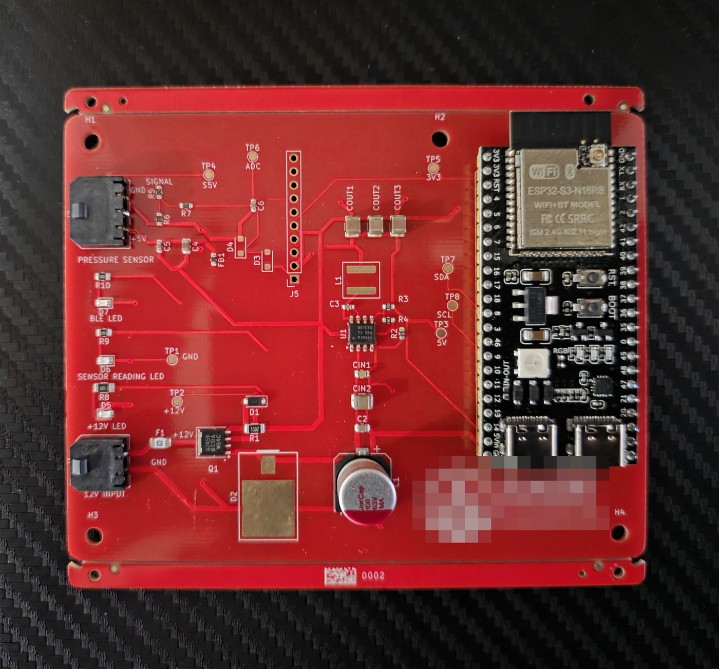 Top view photo of the assembled prototype board with the ESP32-S3 module, the 12 V input and pressure sensor connectors, the buck converter and three status LEDs.